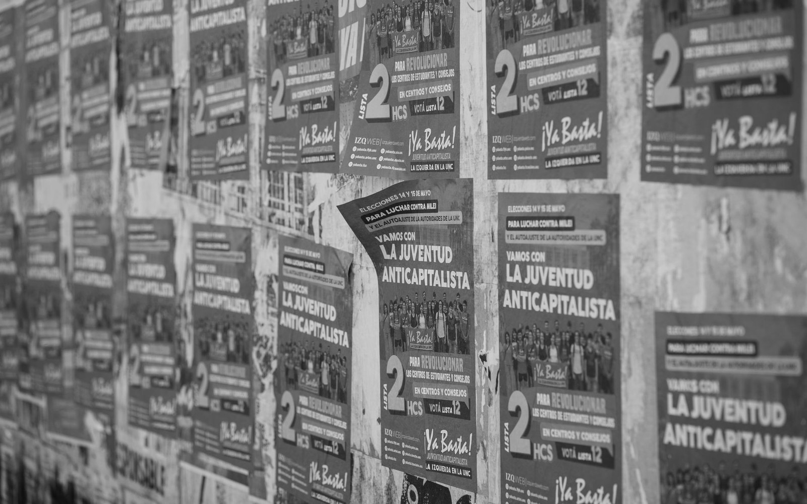 Political campaign posters plastered on a wall reading "la juventud anticapitalista"